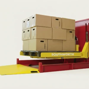 Elevador y nivelador de palets Southworth con plataforma giratoria, cargado con cajas de cartón apiladas y mostrando su rampa de acceso amarilla en la base.